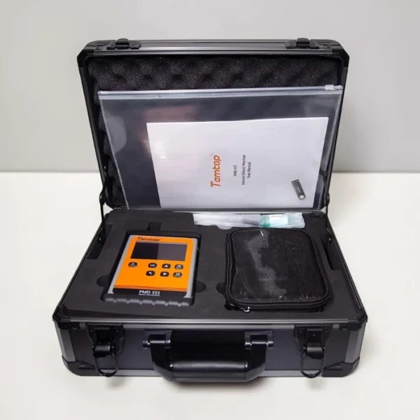 An open black aluminum hard case with protective foam padding containing the orange Temtop PMD351 particle counter, an accessory pouch, and the official user manual document.